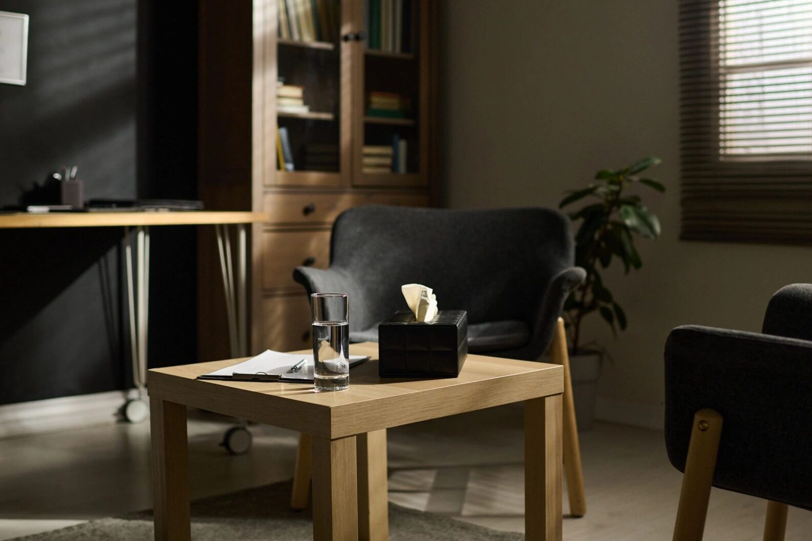 Two comfortable armchairs surrounding small table with box and glass of water